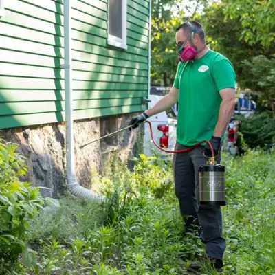 Tech spraying exterior of home